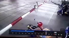 Bungling motorcycle rider gets in a tangle after trying to duck under railway level crossing