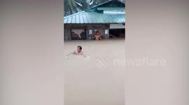 Resident struggles through waist-deep floods to save furniture during tropical storm Choi-wan in the Philippines