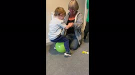 Gran showing toddler how to burst a balloon by bouncing on it