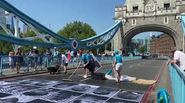 Inside Out Project Tower Bridge Volunteers paste portraits onto the road of tower bridge