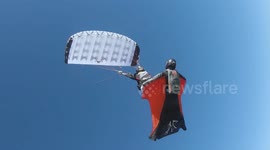 Parachuting athlete SURFS on the back of a wingsuit pilot in impressive docking stunt