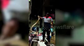 Indian rat snake rescued from wheel of car tipped on its side in south India