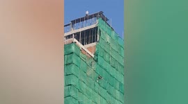 Brave builder stands on top of under-construction tower without safety equipment