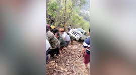 Dozens of Thai locals pull up car that crashed on mountain road