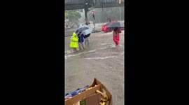 Pedestrians struggle to wade through knee-high floodwater in Washington Heights, US