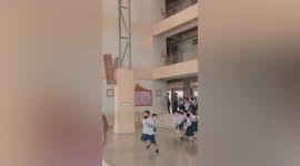 Students energetically run to school exit during fire drill while fire shoots up second floor