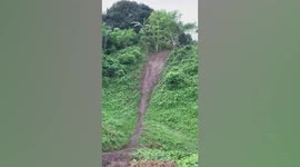 Cyclist flung to the ground after riding through steep slope at dirt track