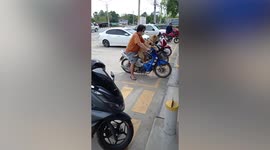 Pet dog patiently waits for owner on motorbike while he buys food at market
