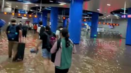 Commuters wade through floodwater as train station submerged in China