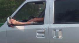 Minibus driver rests foot on wing mirror