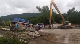Stranded residents use backhoe to cross swollen river due to monsoon rain in the Philippines