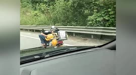 Delivery driver spotted lying down while driving scooter along road in southern China
