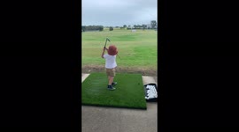 Little boy playing golf at the driving range and hitting like a pro