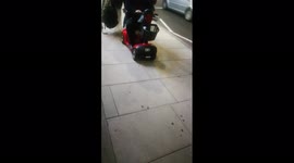 Mobile scooter breaks down at night in Holloway Rd London. Friends help push it home.