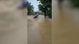 Three daring youngsters risk their lives crossing over a flooded area in central India