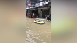 Foreigner rides inflatable dingy through flash floods in Thailand