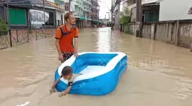 Man rides inflatable dingy through flash floods in Thailand