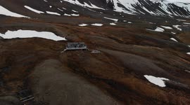 Svalbard (Spitsbergen) drone view. Glacier in spring, mountains view near Longyearbyen. People waving, small hut.