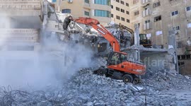 Palestinian workers use a bulldozer to remove the rubbles of a building which was hit by Israeli strikes during the recent conflict between Israel and Hamas