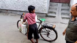 A funny tiffen tiny dilevery boy do with running by bycicle in Indian street way