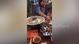 Determined locals carry on with BBQ despite flooded restaurant in Thailand
