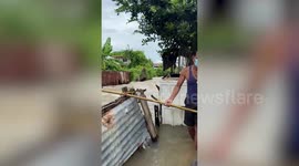 Neighbours use makeshift pulley to send food to woman stranded in flood in Thailand