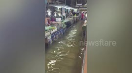 Marketgoers walk through flooded aisles after heavy rain in Thailand