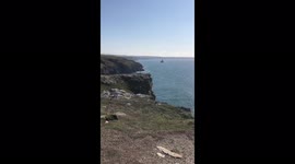 Shocking footage shows daredevil tourists casually sitting and JOGGING on edge of steep cliff – near spot where fisherman died last year