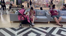Woman holds pet chihuahua inside shopping mall waiting area