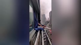 Resident holds hose out of window to help extinguish neighbour's flat in southern China