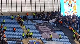Violence erupts in the stands at a football match - above large banner of Jimmy Hill