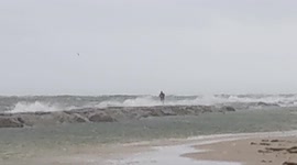 A fisherman casts into the ocean during sustained 30 mph winds in the middle of a storm