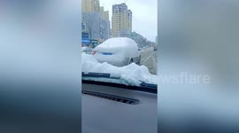 Chinese motorist spotted driving along road in car covered by thick blanket of snow