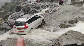 Car stuck on flooded road by rain-triggered landslide in northern India