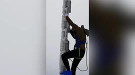 Weather station staff scrape ice off pole on top of mountain in southern China