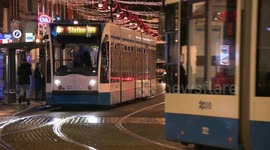 Public transportation, cyclists and pedestrians on a street with Christmas decorations in Amsterdam, Holland