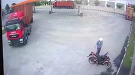 Motorcycle rider putting air in his tires almost run over by truck at petrol station