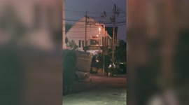 Thai men relax drinking beer while fire rages behind them