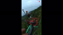 Rider slips off bike while riding a zipline several feet above the ground