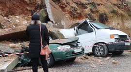 Palestinians in Ramallah inspect cars crushed by collapse of residential building's sidewall after rain storms