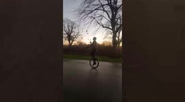 Guy rides unicycle while juggling three balls on road in Nottingham, England
