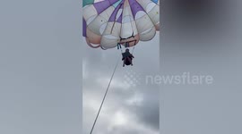 Workaholic tourist types away on laptop while floating on parasail