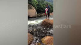 Elderly woman feeds hundreds of fish near waterfall