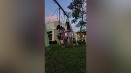 Two girls fall backwards off garden swing in the Philippines