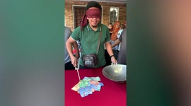 Blindfolded man scoops money using spatula in bizarre party game in Malaysia