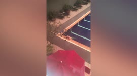 Tourist rubs shampoo into hair while relaxing in swimming pool in Cambodia