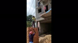 Construction workers form a crane to transport bricks to higher elevations in the absence of machineries in South India