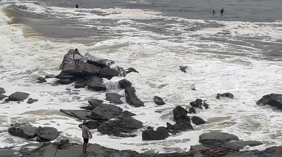 Australian surfer washed off rocks by a big wave as he tries to enter the rough stormy ocean with big waves