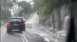 Roadside 'waterfall' formed as Sydney inundated by deadly flooding