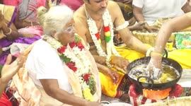 Granny uses bare hands as a strainer to remove the donut like snack from the boiling oil.